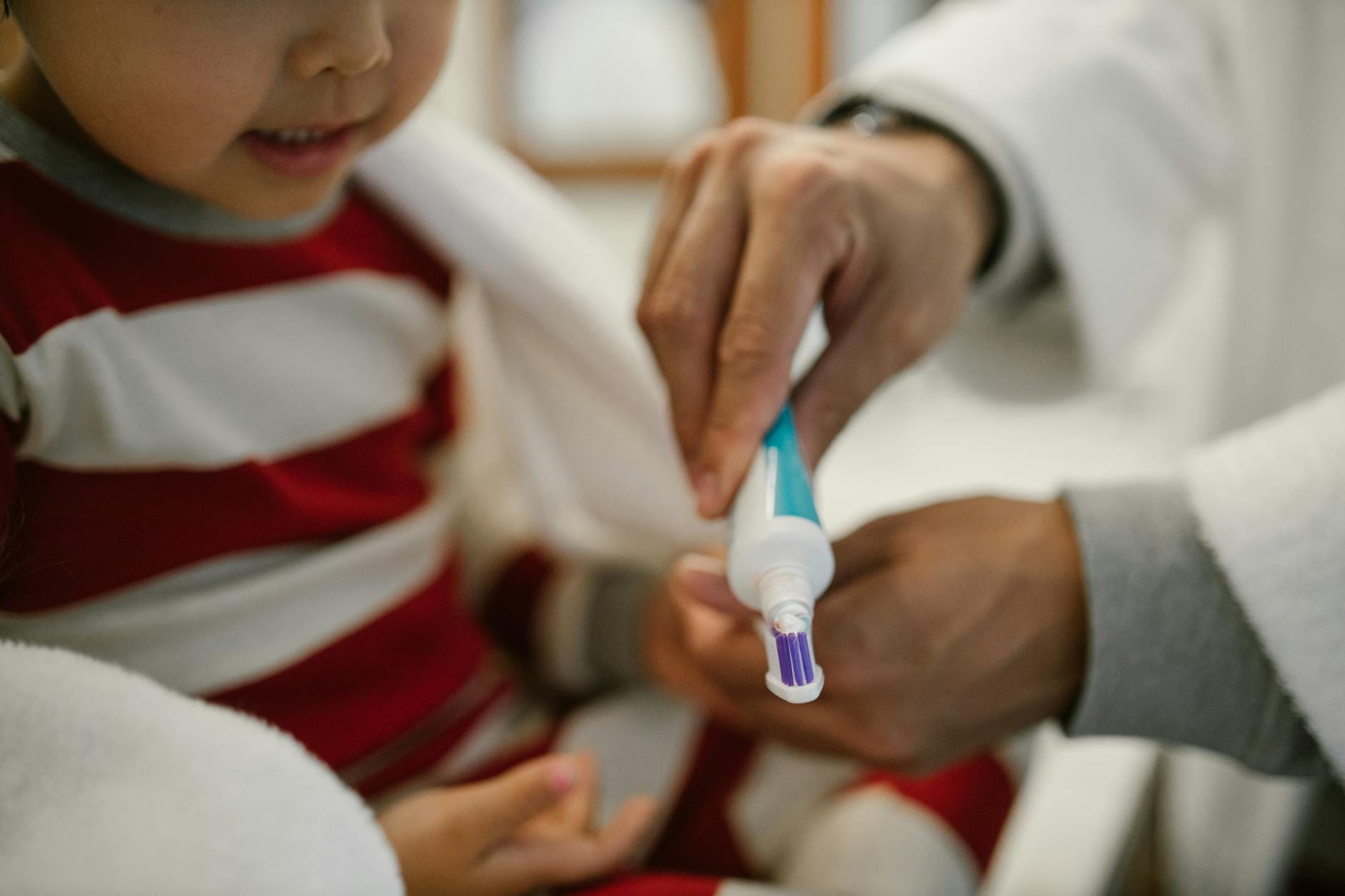 Tata pomaga córce nałożyć pastę na szczoteczkę do zębów