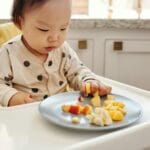 Żelazo w diecie przedszkolaka: produkty, które naprawdę pomagają Małe dziecko je świeże owoce przy kuchennym blacie