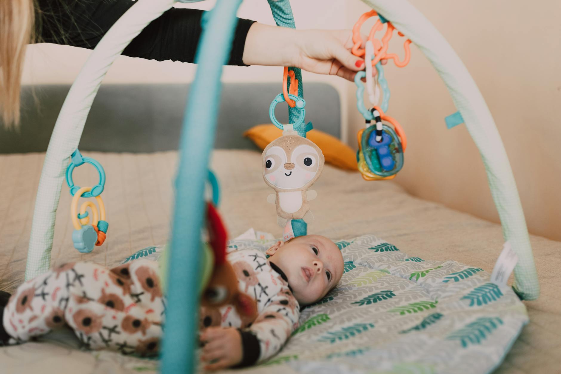 Niemowlę leżące na macie edukacyjnej z kolorowymi wiszącymi zabawkami